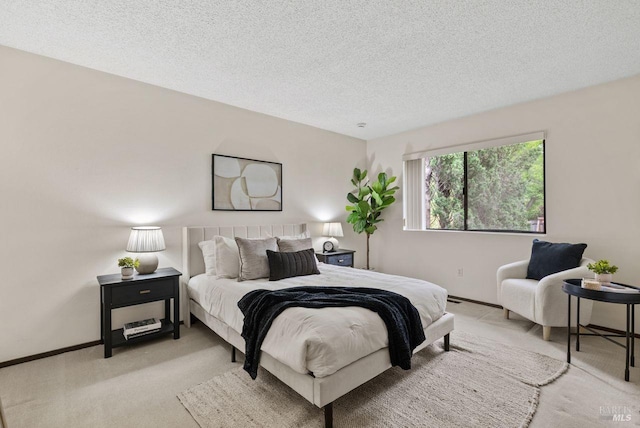 bedroom featuring a textured ceiling, light colored carpet, and baseboards