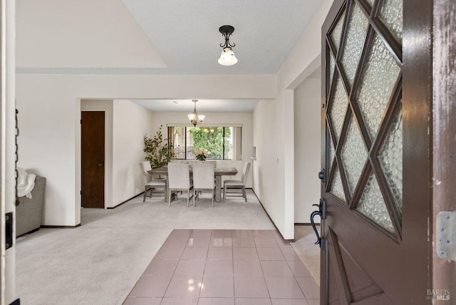 carpeted foyer entrance featuring baseboards, tile patterned floors, and a chandelier