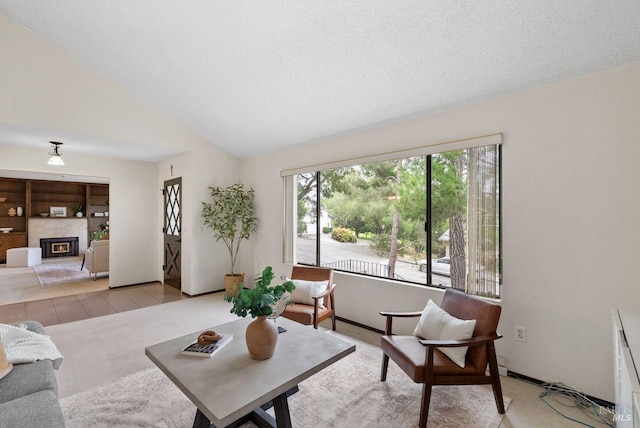 living room with carpet floors, baseboards, a glass covered fireplace, and vaulted ceiling