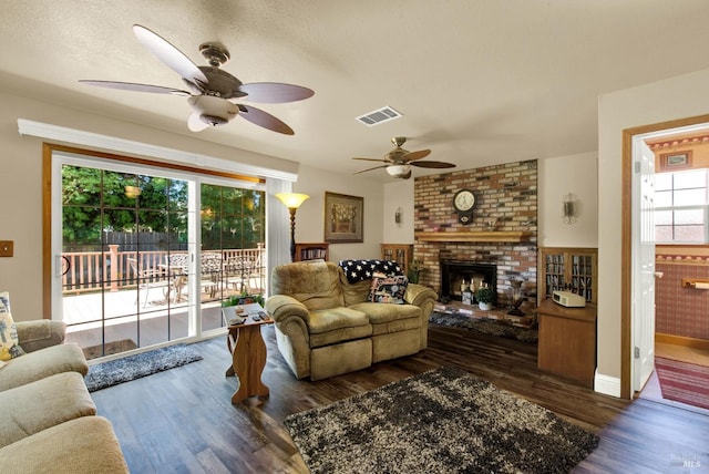 living room with a ceiling fan, visible vents, wood finished floors, and a fireplace