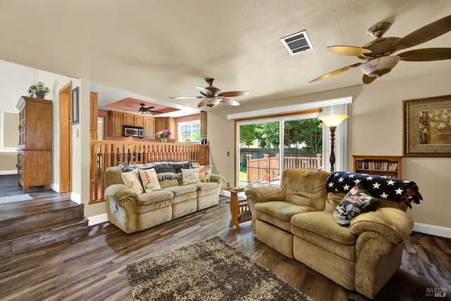 living room with visible vents, a ceiling fan, baseboards, and dark wood finished floors