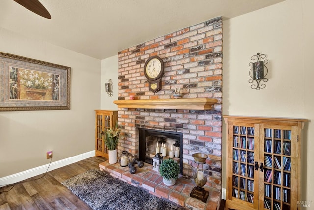 living room with baseboards, a fireplace, and wood finished floors