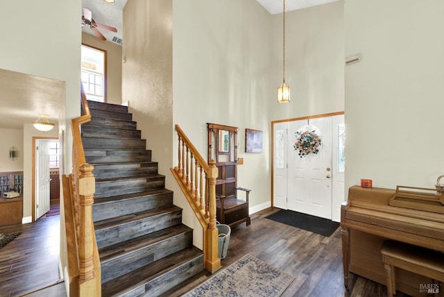 foyer entrance with stairway, a high ceiling, a ceiling fan, and dark wood-style flooring