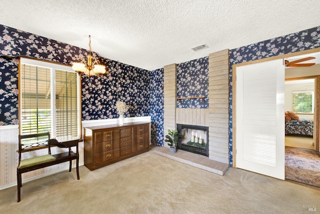 bathroom featuring a textured ceiling, visible vents, a fireplace, a notable chandelier, and wallpapered walls
