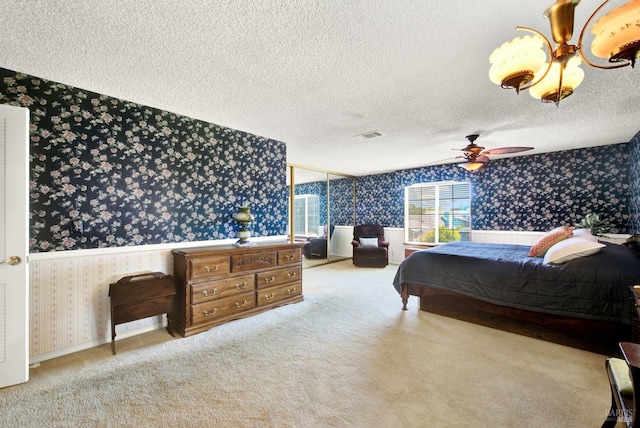 carpeted bedroom featuring a wainscoted wall, wallpapered walls, and a textured ceiling