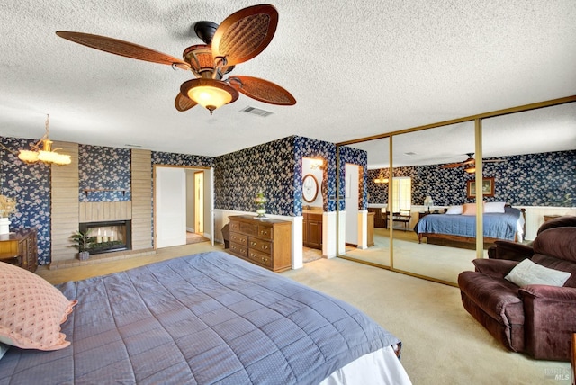 bedroom featuring a brick fireplace, wallpapered walls, a textured ceiling, a ceiling fan, and carpet