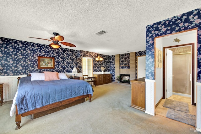 bedroom with visible vents, a textured ceiling, light colored carpet, and wallpapered walls