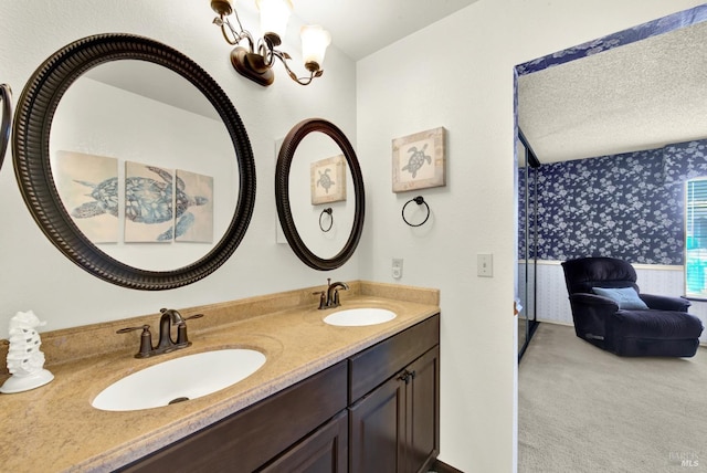 full bath featuring double vanity, wallpapered walls, a sink, and ensuite bathroom