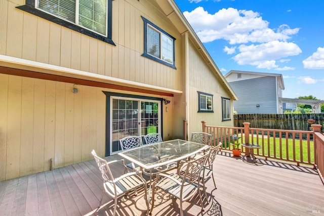 wooden terrace featuring a lawn, fence, and outdoor dining area