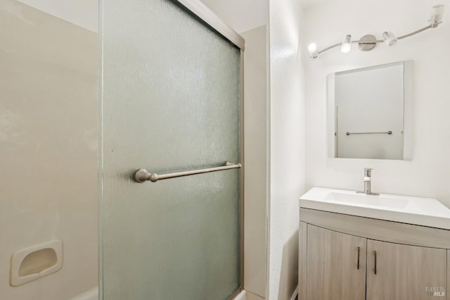 bathroom featuring a shower with door and vanity