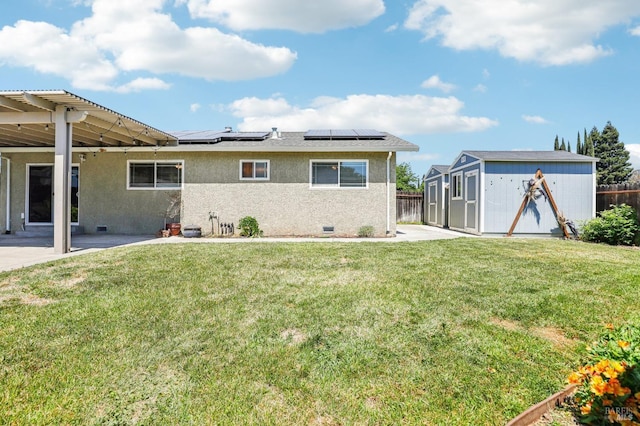 back of house featuring an outdoor structure, fence, a shed, stucco siding, and roof mounted solar panels