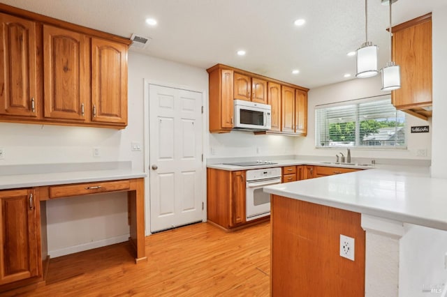 kitchen with visible vents, brown cabinets, a peninsula, light wood-style floors, and white appliances