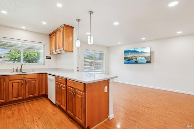kitchen with a sink, light wood-style flooring, a peninsula, and a healthy amount of sunlight