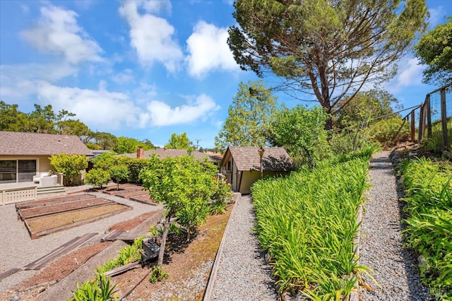 view of yard with a storage shed, an outbuilding, and a vegetable garden