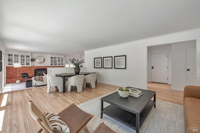 living room featuring light wood-style floors, baseboards, crown molding, and a fireplace