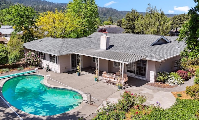 pool featuring a view of trees and a patio area