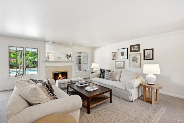 living area with baseboards, a wealth of natural light, light carpet, and a tile fireplace