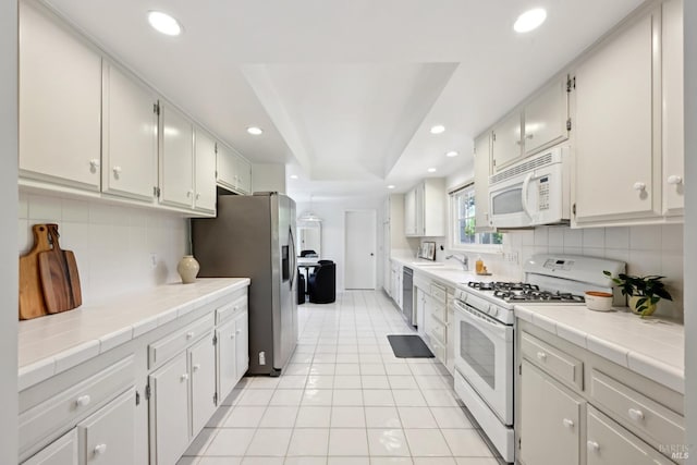 kitchen featuring light tile patterned flooring, a sink, white appliances, recessed lighting, and backsplash