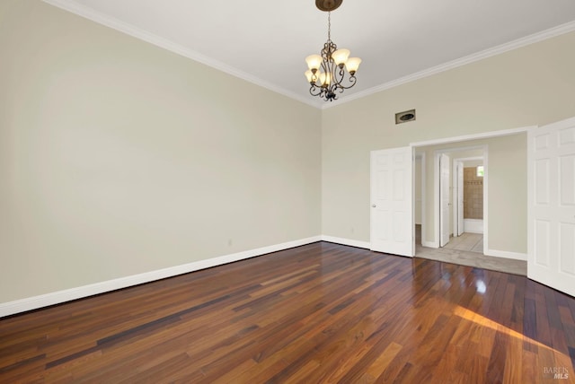 empty room featuring baseboards, ornamental molding, wood finished floors, and a notable chandelier