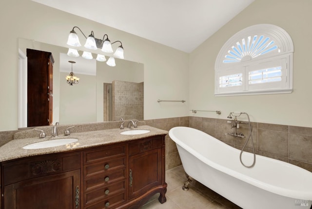 full bathroom with tile walls, tile patterned floors, a freestanding bath, and a sink