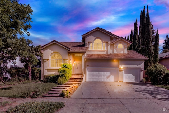 view of front of property with a tiled roof, a garage, stucco siding, and driveway