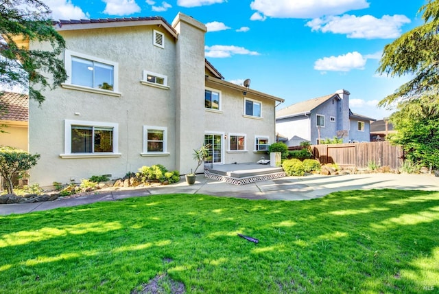 back of house with a lawn, fence, a patio area, and stucco siding