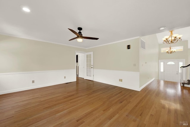 spare room featuring wainscoting, ceiling fan with notable chandelier, baseboards, wood finished floors, and visible vents