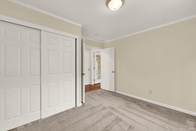 unfurnished bedroom featuring carpet floors, crown molding, baseboards, and a closet