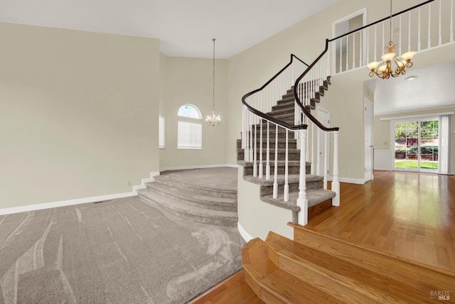stairs with baseboards, an inviting chandelier, and a towering ceiling