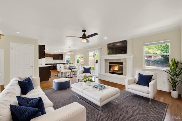 living area featuring a ceiling fan, a healthy amount of sunlight, light wood finished floors, and a fireplace