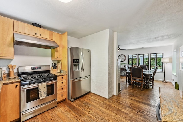 kitchen featuring a ceiling fan, appliances with stainless steel finishes, under cabinet range hood, and hardwood / wood-style flooring