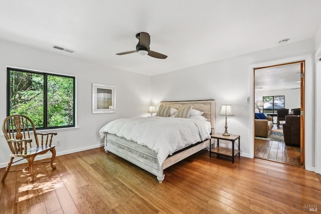 bedroom featuring visible vents, baseboards, ceiling fan, and hardwood / wood-style flooring