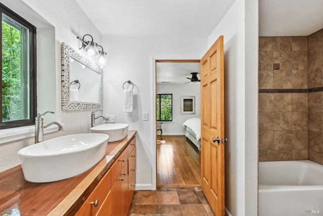 ensuite bathroom with a sink, a washtub, double vanity, and connected bathroom