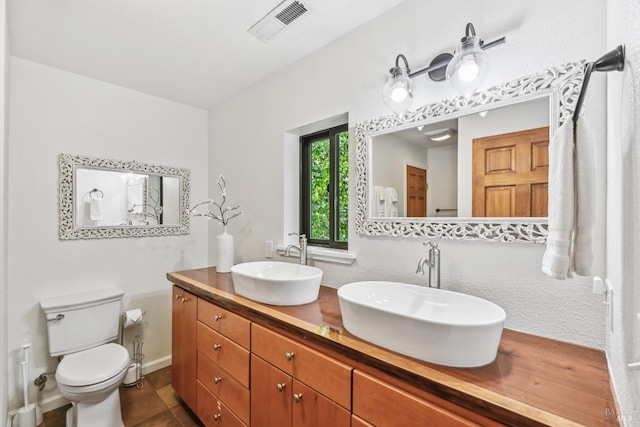 bathroom with a sink, toilet, double vanity, and visible vents