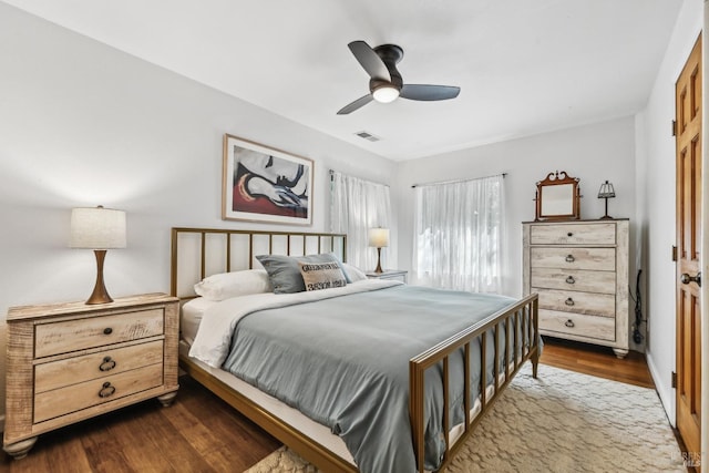 bedroom with a ceiling fan, visible vents, and dark wood-type flooring