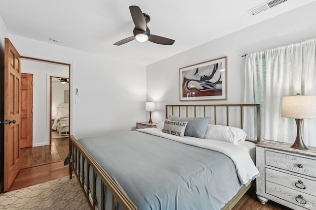 bedroom with a ceiling fan, visible vents, and wood finished floors