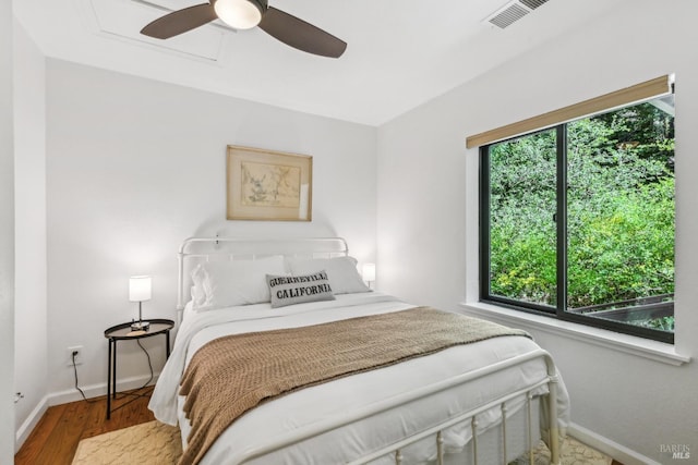bedroom with visible vents, baseboards, wood finished floors, and multiple windows
