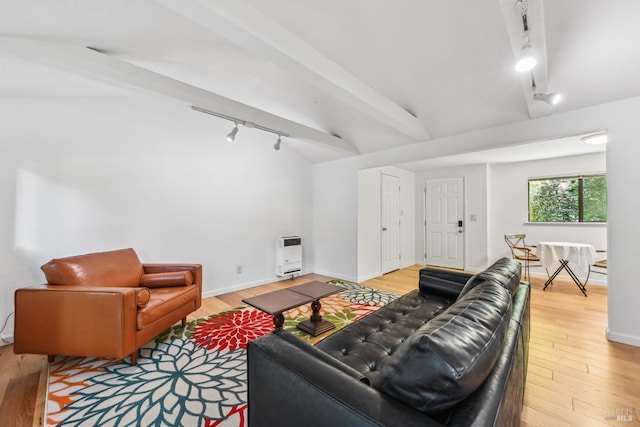 living area featuring track lighting, heating unit, baseboards, vaulted ceiling with beams, and light wood finished floors