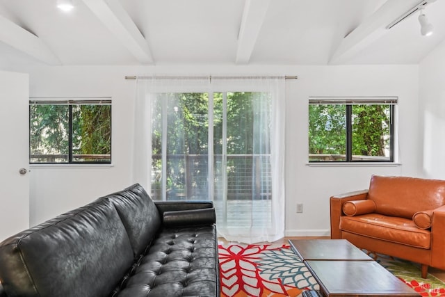 living area with baseboards and vaulted ceiling with beams