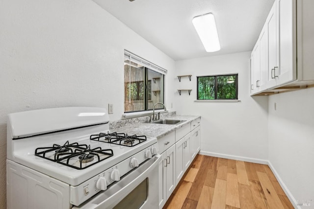 kitchen with white cabinets, a sink, light wood-style floors, light countertops, and white range with gas cooktop
