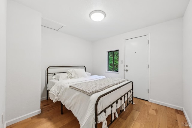 bedroom featuring baseboards, wood finished floors, and attic access