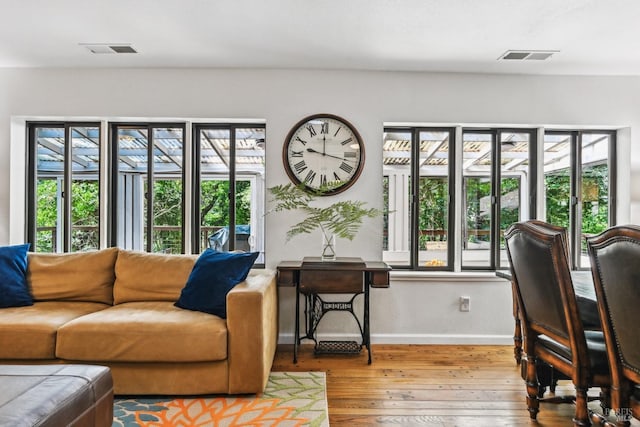 living room with baseboards, visible vents, a healthy amount of sunlight, and hardwood / wood-style flooring