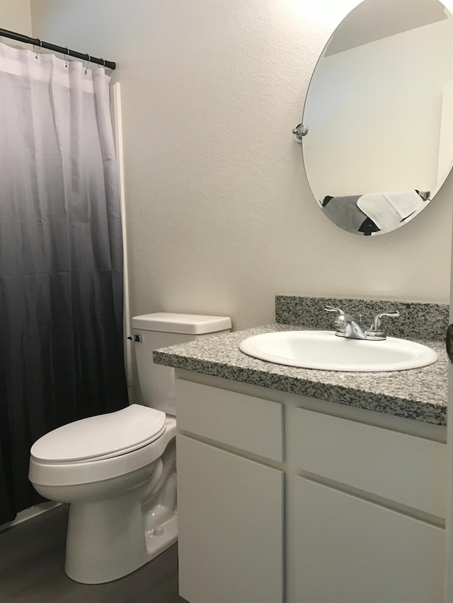 full bathroom with vanity, toilet, curtained shower, and wood finished floors