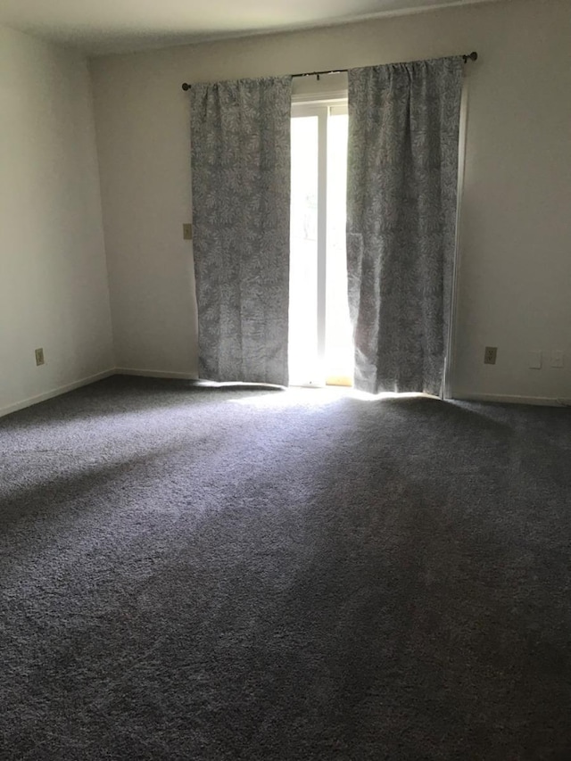 carpeted spare room featuring baseboards