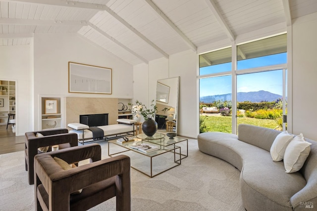 carpeted living room featuring wood ceiling, beam ceiling, high vaulted ceiling, a mountain view, and a premium fireplace
