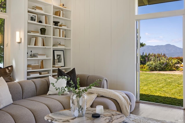 living room with built in shelves, a mountain view, and wood finished floors