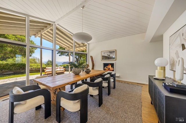dining space with lofted ceiling with beams, baseboards, and light wood-style floors