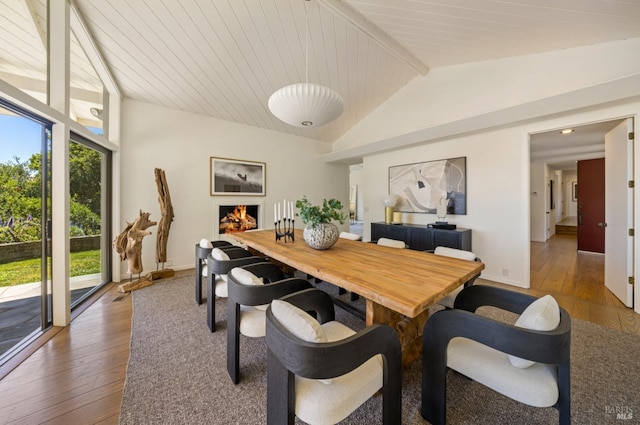dining space with baseboards, hardwood / wood-style floors, and vaulted ceiling
