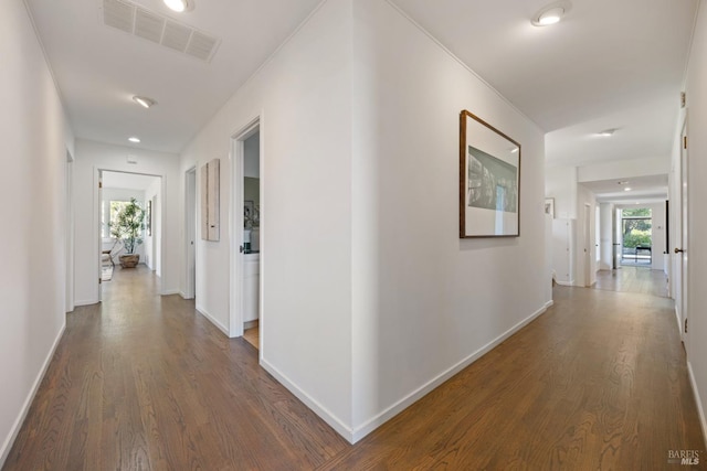 hallway featuring visible vents, dark wood-style flooring, and baseboards