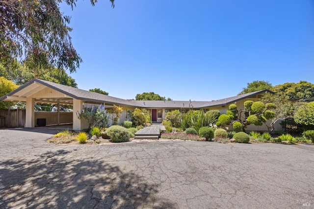 ranch-style home featuring fence and aphalt driveway